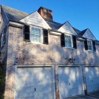 A Brick House With White Garage Doors And Black Shutters — Lititz, PA — Trailside Spouting, LLC