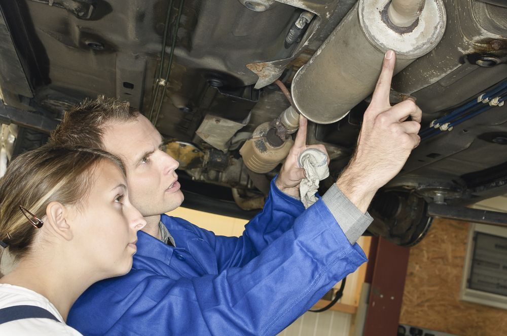 A Man And A Woman Are Looking At The Underside Of A Car — Jasco Automotive In Bowen, QLD