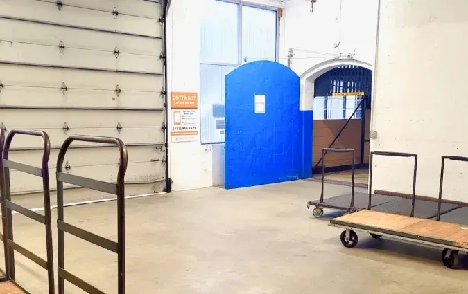 Interior warehouse space with open loading dock door, blue door, and carts.