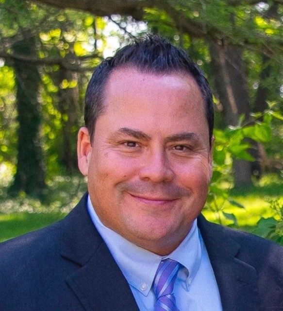 A man in a suit and tie is smiling for the camera.