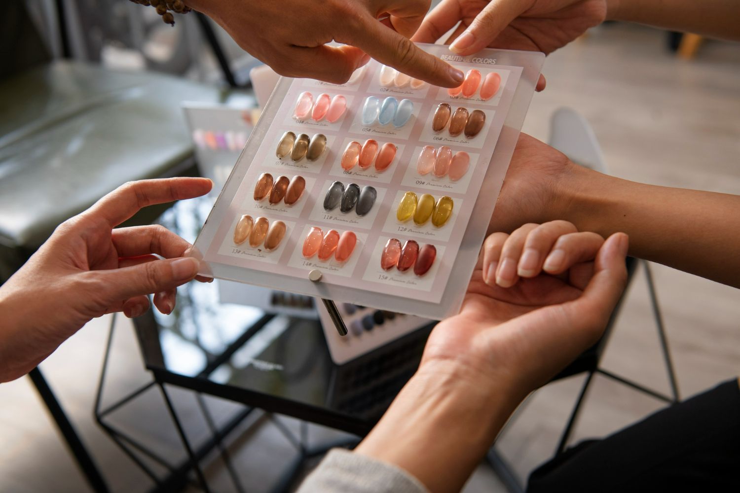 Hands holding nail polish color samples, pointing to options for a manicure.