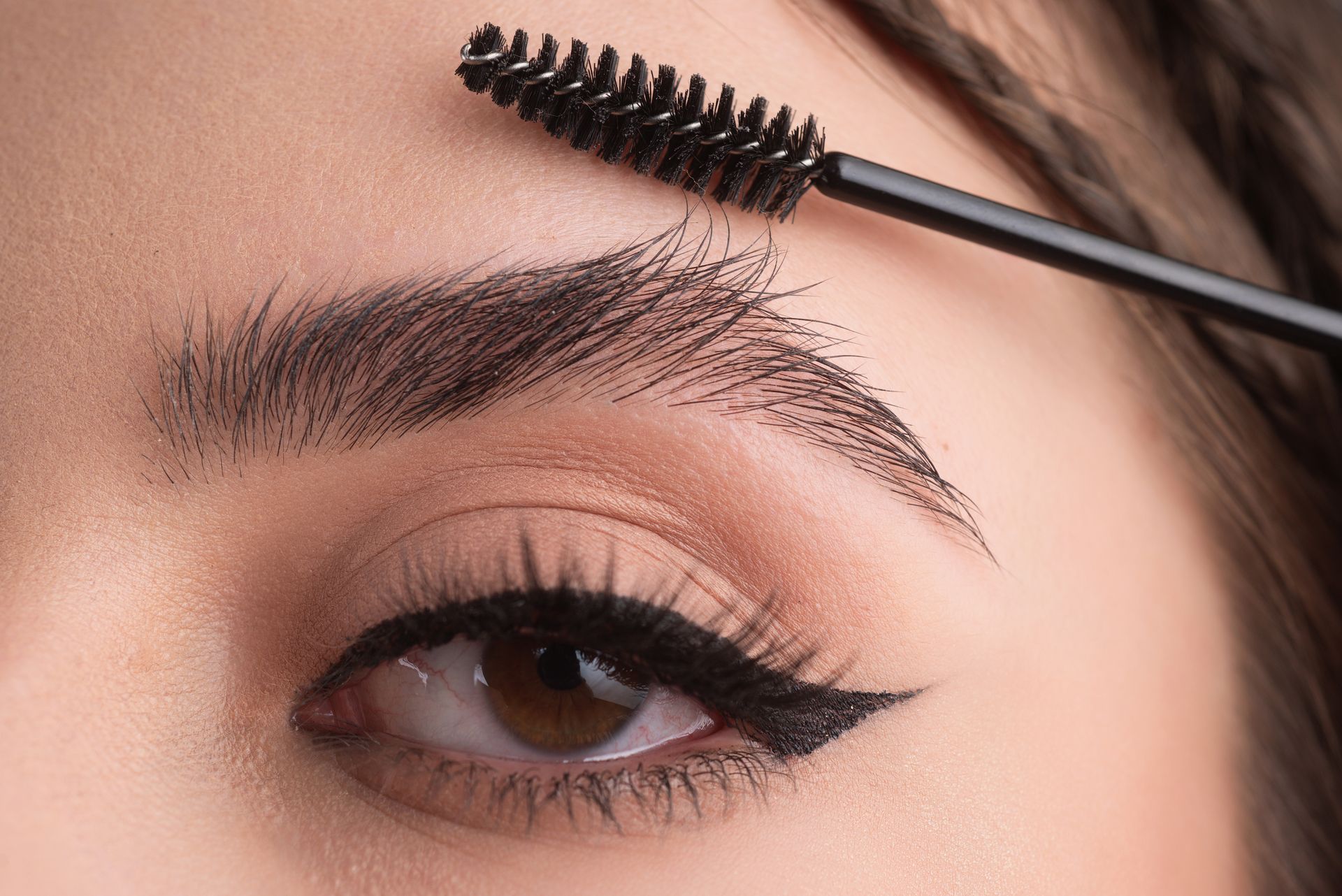 a woman is applying mascara to her eyebrows .