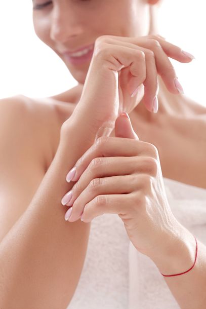 a woman is applying lotion to her hands and smiling .