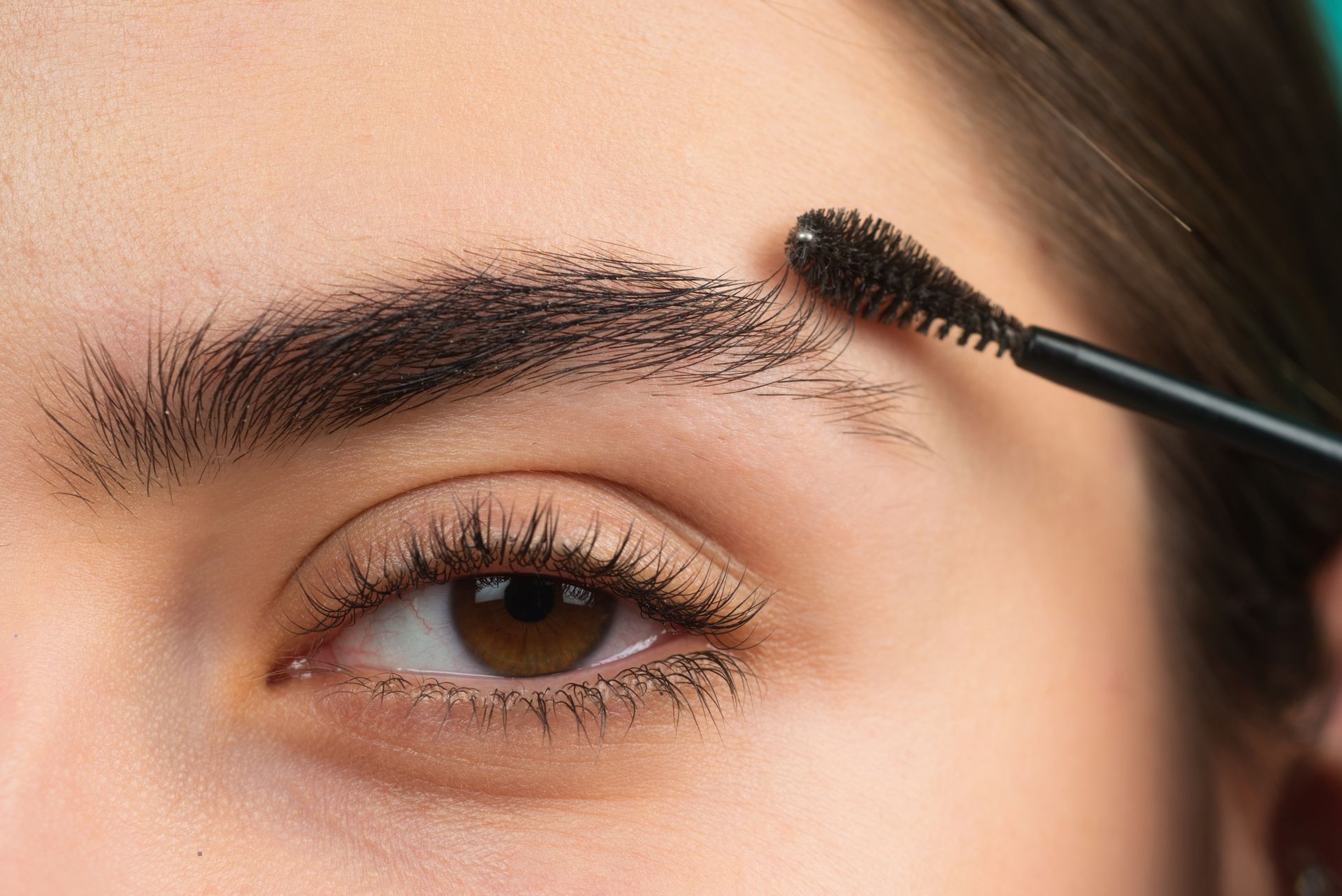 a woman is applying mascara to her eyebrows .