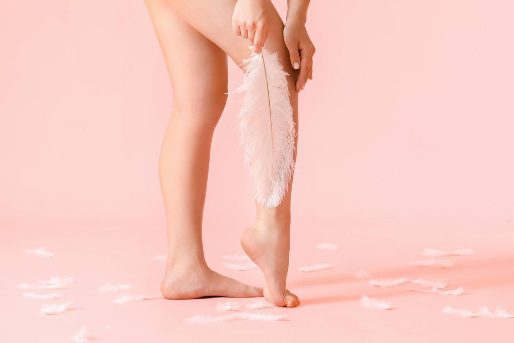 a woman is holding a white feather on her leg .