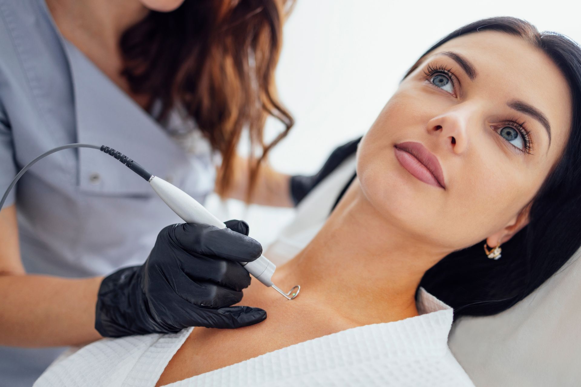 a woman is getting a skin tag removal treatment on her neck .