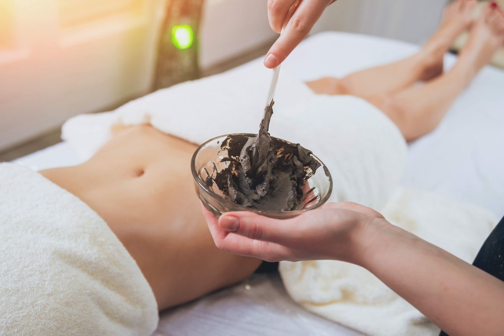 a woman is getting a massage with a bowl of mud on her stomach .