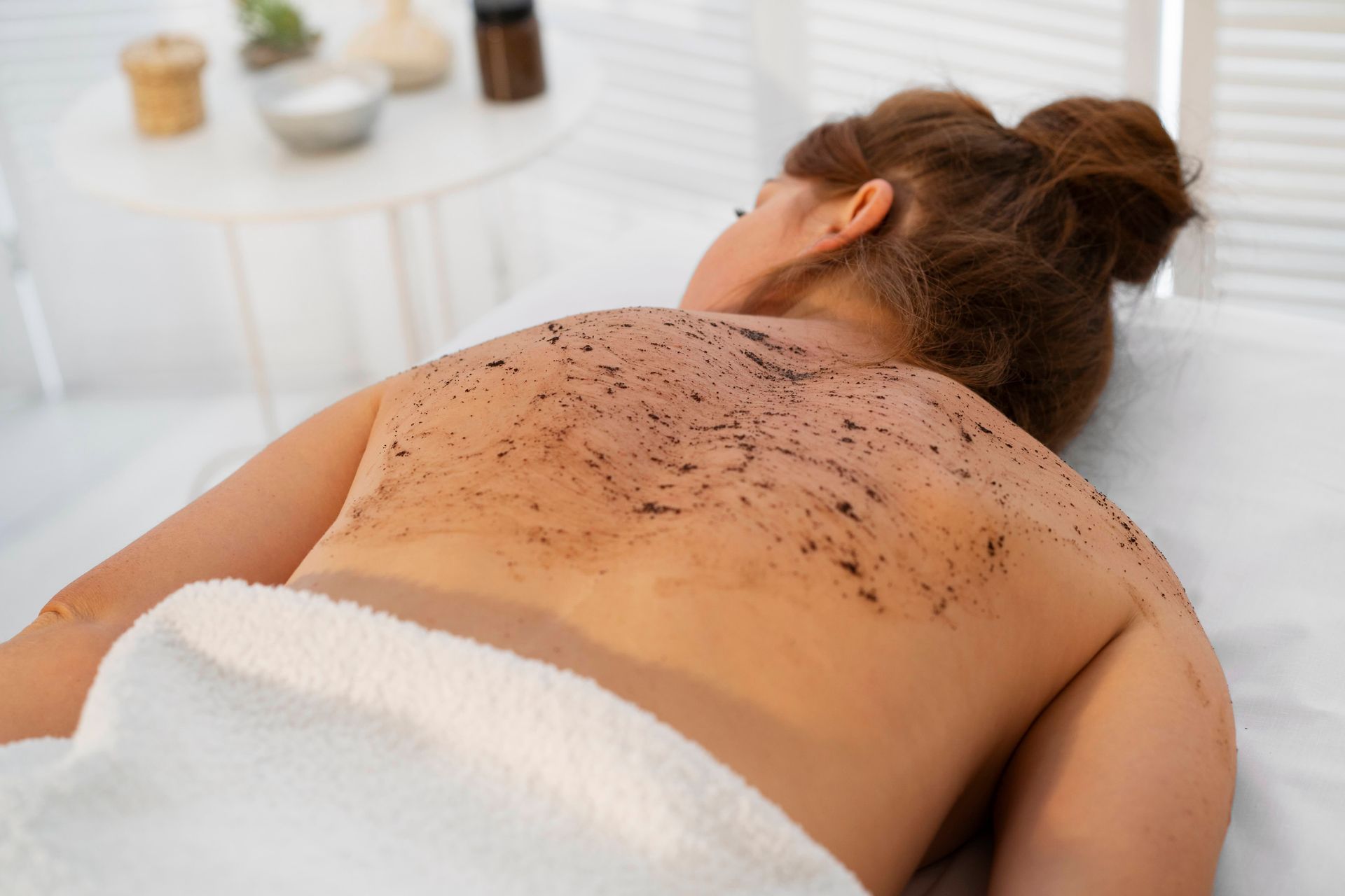 a woman is getting a body scrub on her back at a spa .