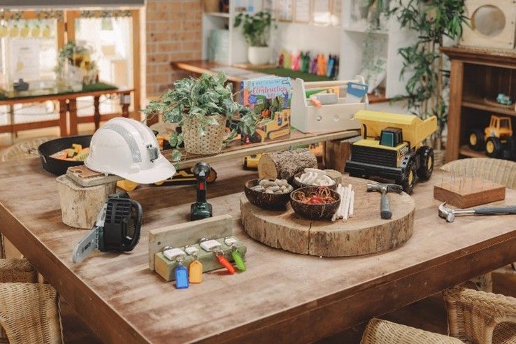 A wooden table with toys and a hard hat on it.
