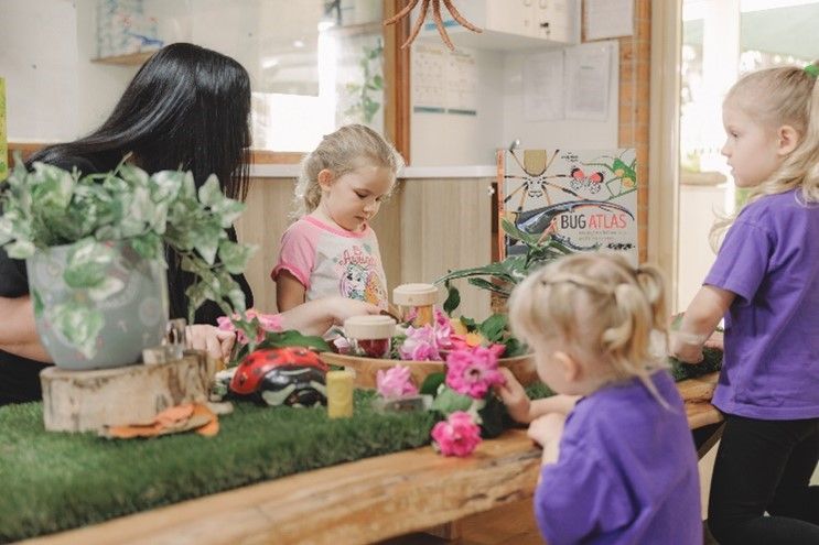 A group of young girls are playing with toys at a table.