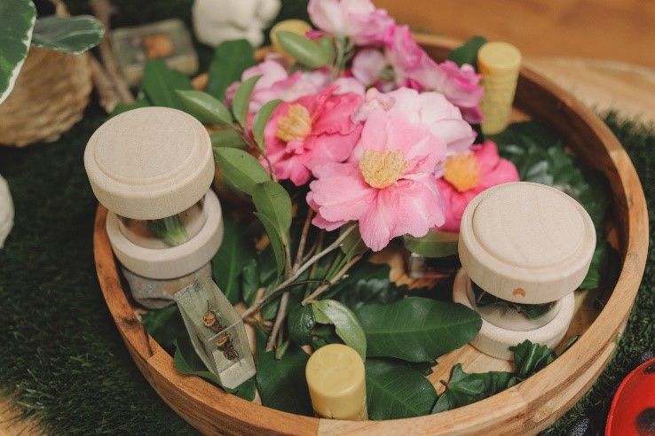 A wooden bowl filled with flowers and leaves on a table.