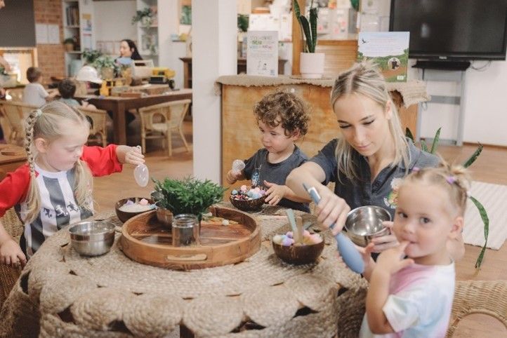 A woman is sitting at a table with three children.