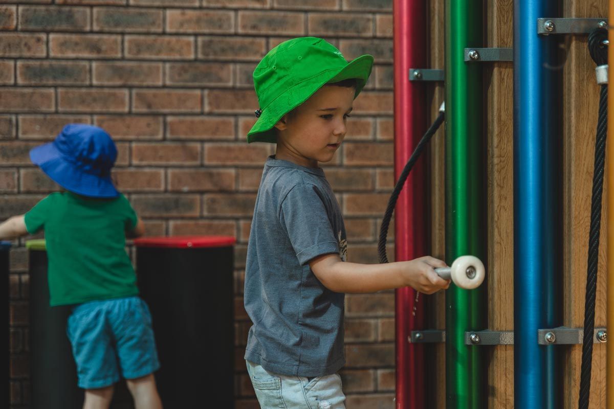 A young boy in a green hat is playing with a toy.