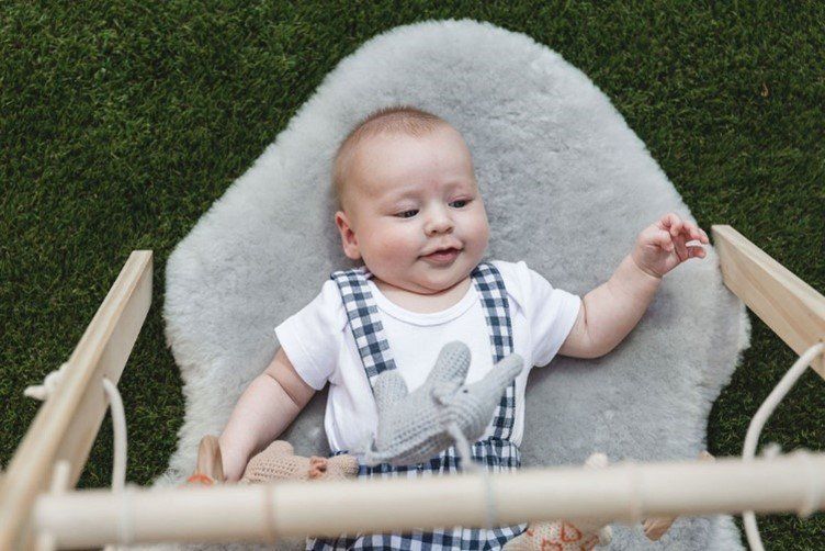 A baby is laying on a blanket in a crib.