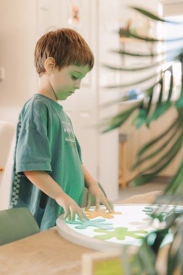 A young boy is playing with a light box on a table.
