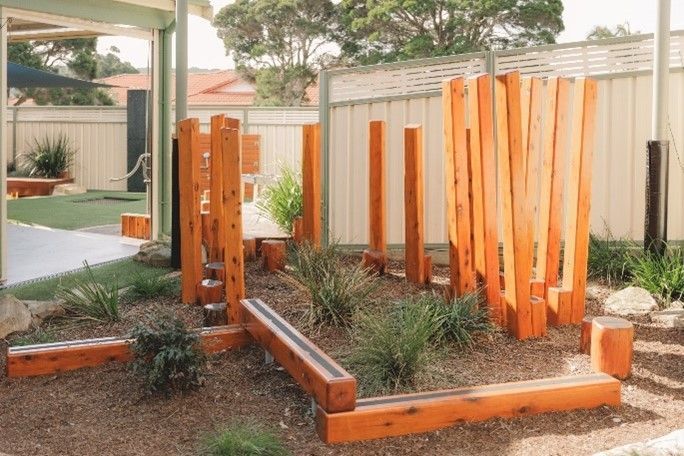 A wooden playground in a backyard with a fence in the background.