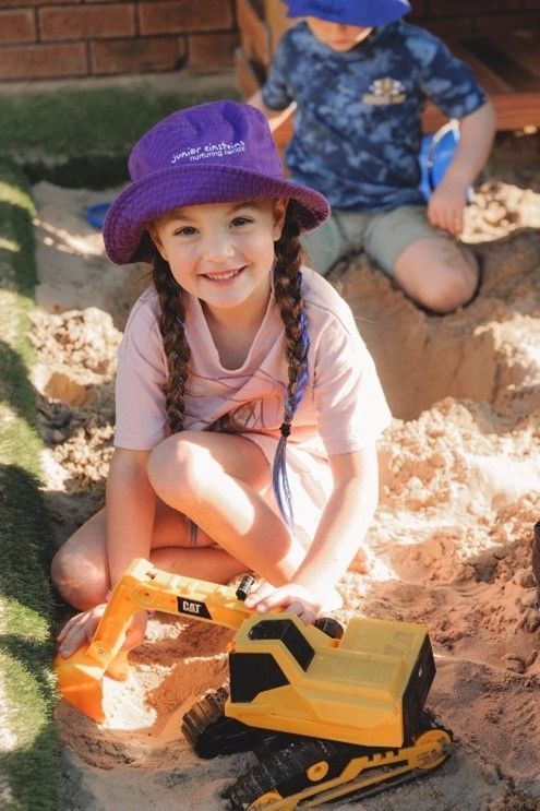 A smiling girl playing on the sand.