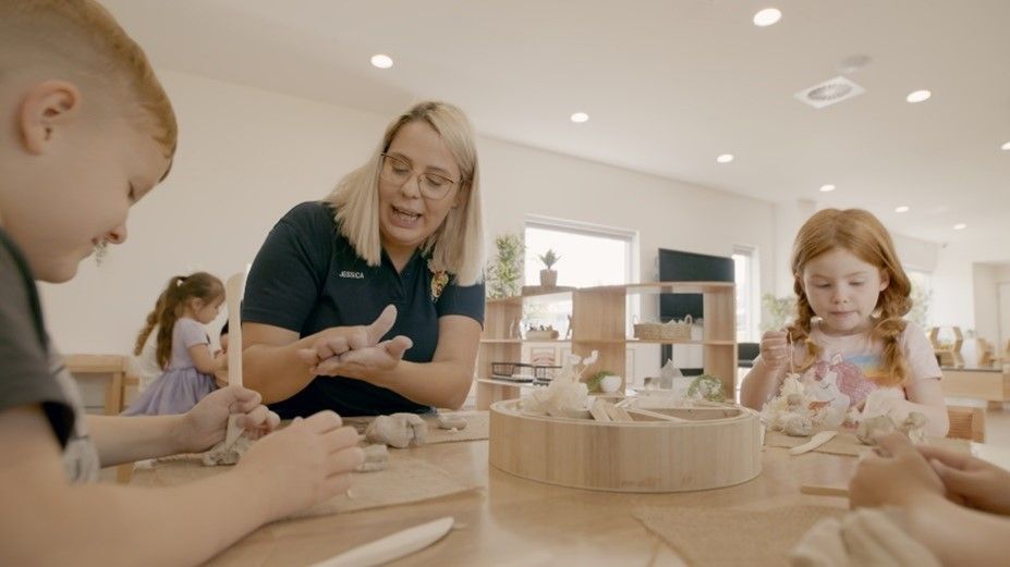 A woman is teaching children how to make clay in a classroom.