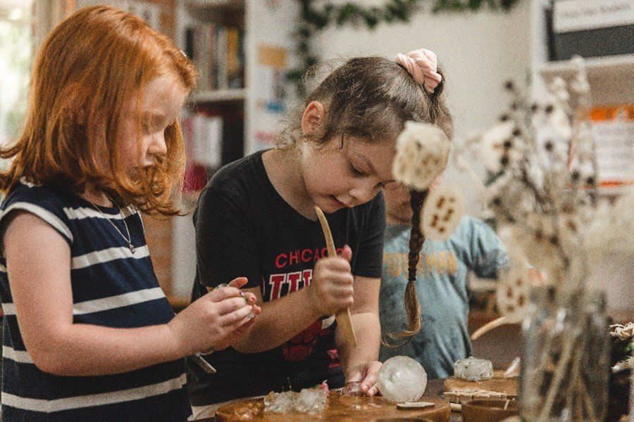 A group of young girls are playing with a wooden hammer.