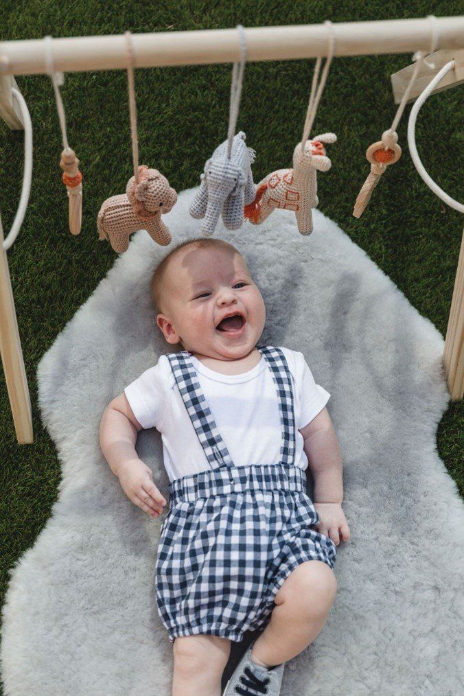 A baby is laying on a blanket in a play gym.