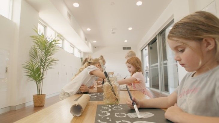 A group of young girls are sitting at a table painting.