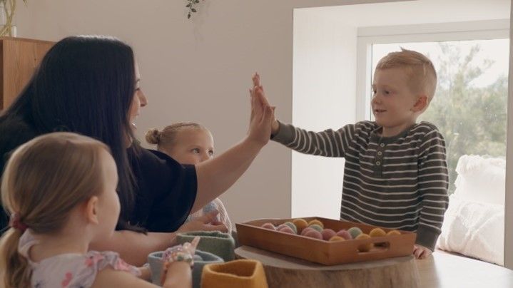 A woman and two children are giving each other a high five.