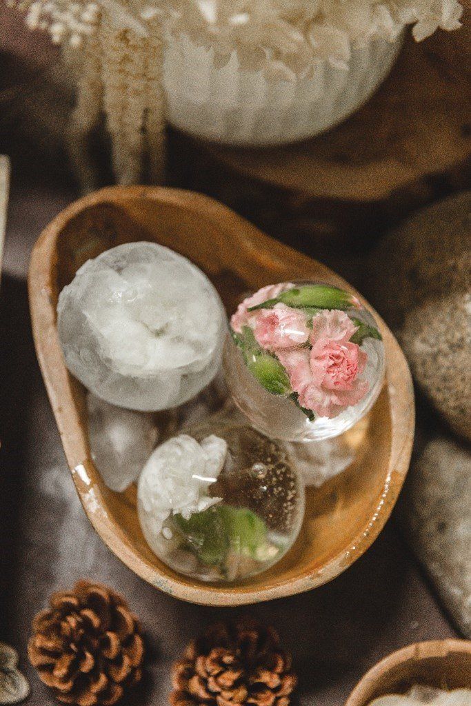 A wooden bowl filled with ice cubes and flowers.