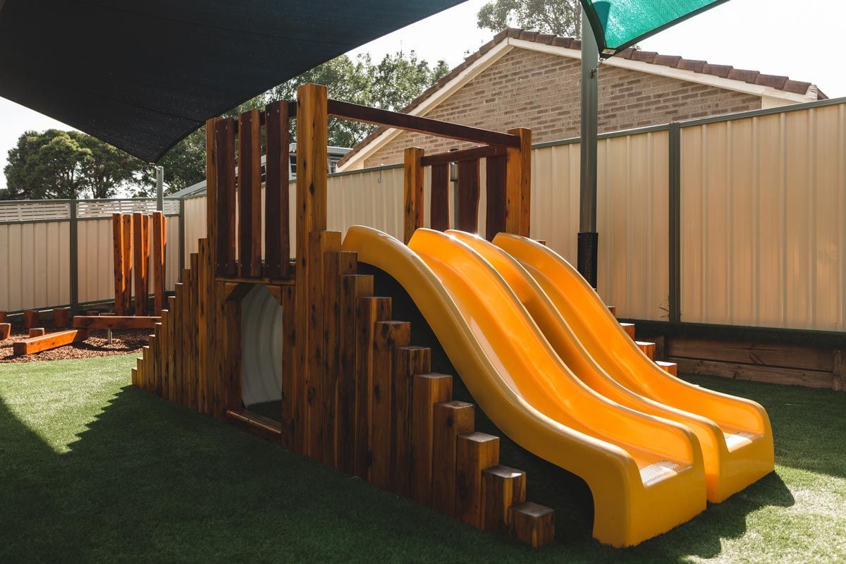 A wooden playground with a yellow slide and stairs.