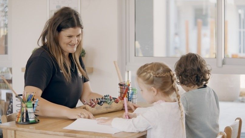 A woman is sitting at a table with two children.
