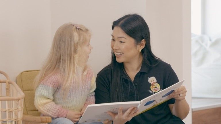 A woman is reading a book to a little girl.