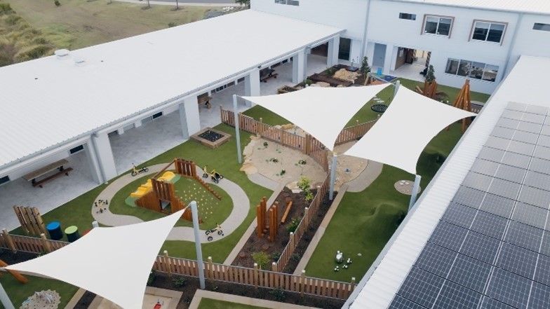 An aerial view of a playground with umbrellas and solar panels.