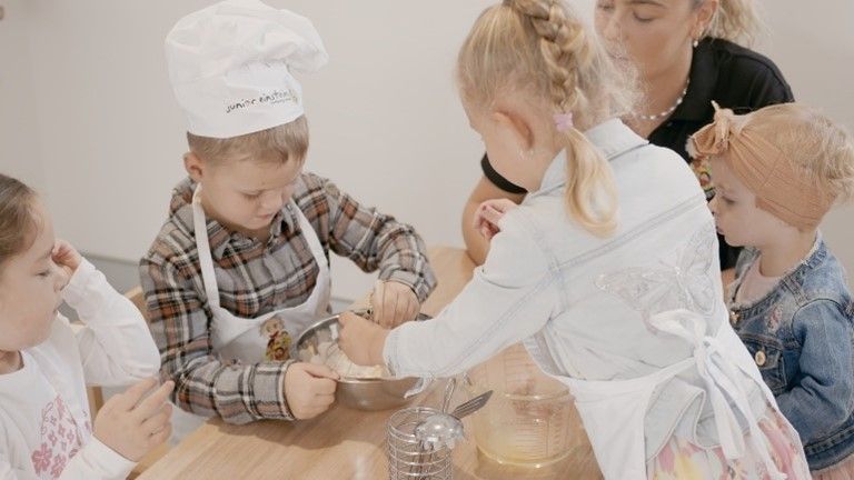 A group of children are sitting at a table preparing food.