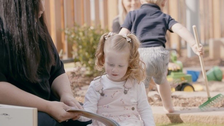 A woman is reading a book to a little girl.