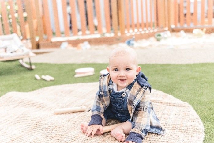 A baby is laying on a blanket on the grass.