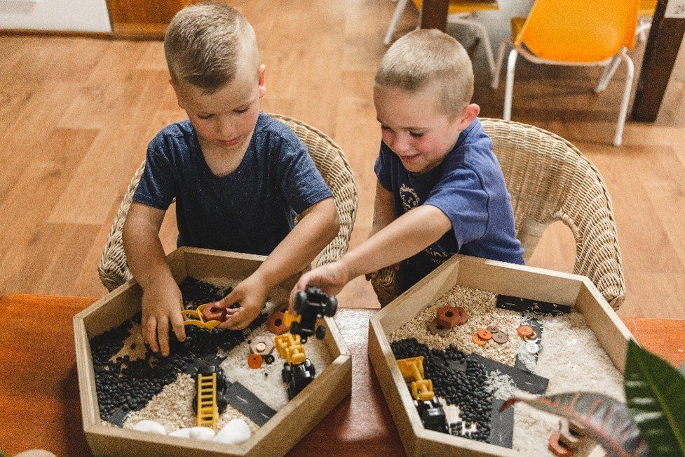 Two young boys are playing with toys in a sandbox.