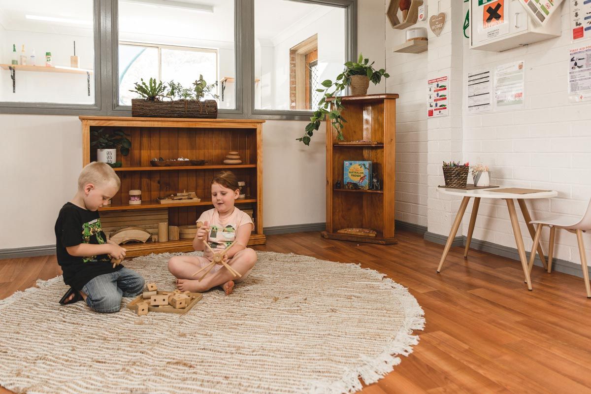 A boy and a girl are sitting on the floor playing with blocks.