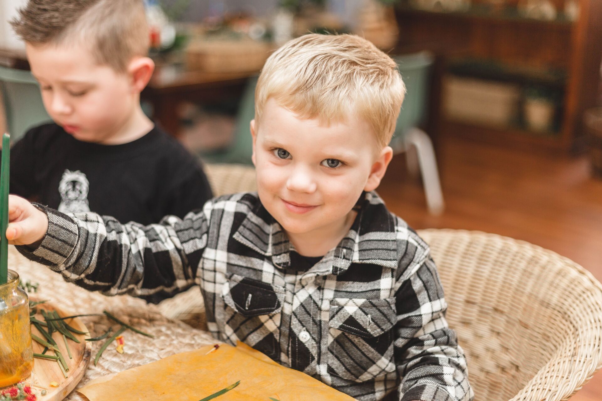 A young boy in a plaid shirt is sitting at a table.