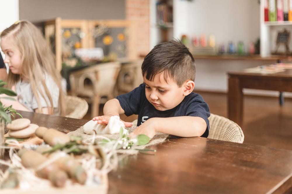 A young boy is sitting at a table playing with rocks.
