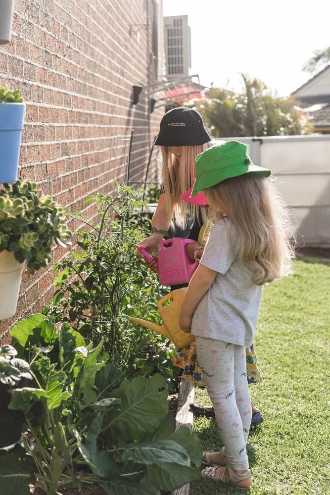 Two girls helping to water the plants