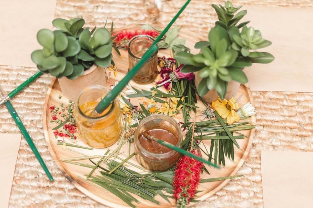 A wooden tray filled with flowers , plants , and brushes.