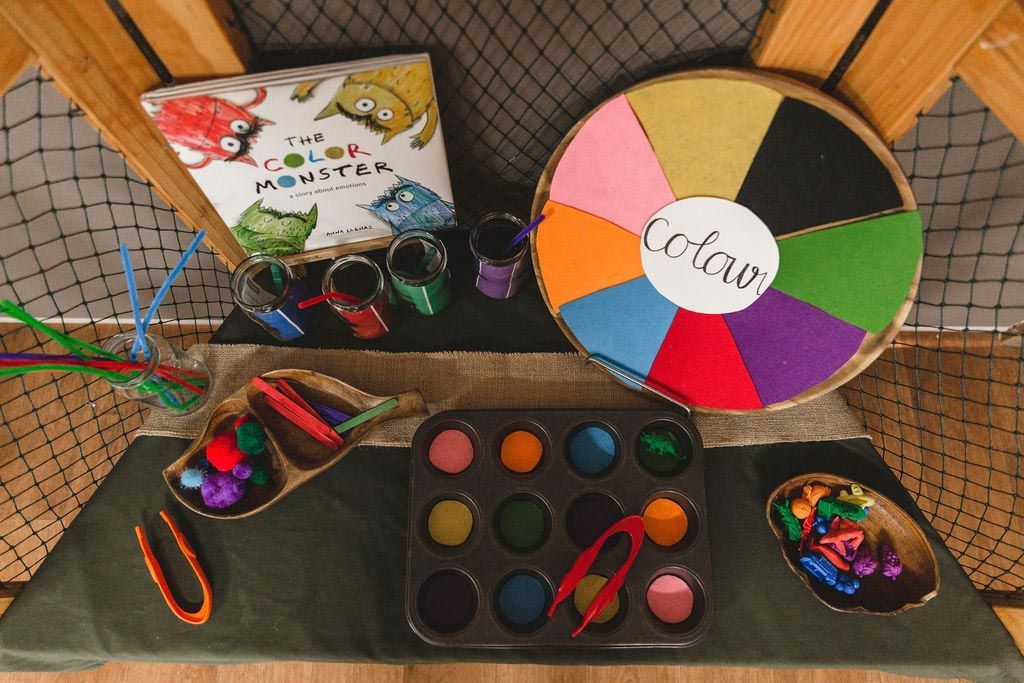 A table with a spinning wheel and a book called the color monster