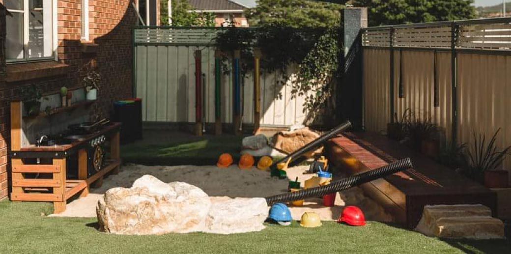 A backyard filled with lots of toys and a sandbox.