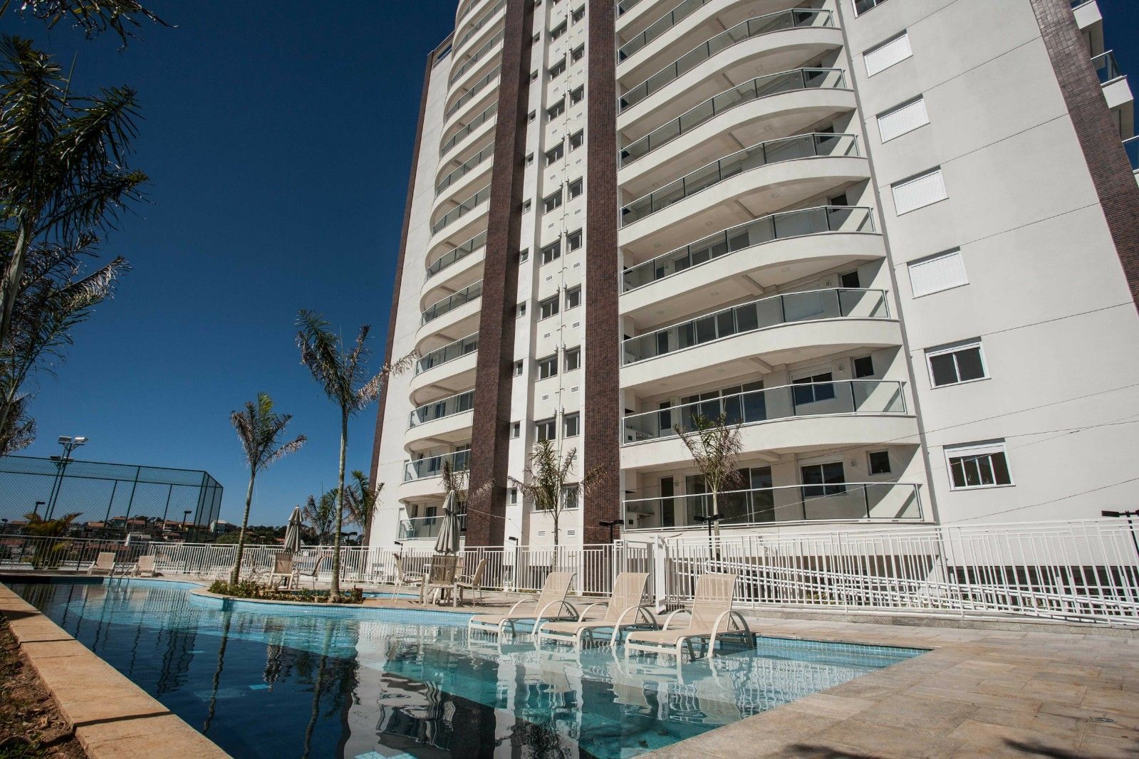 Um edifício alto com uma piscina na frente.