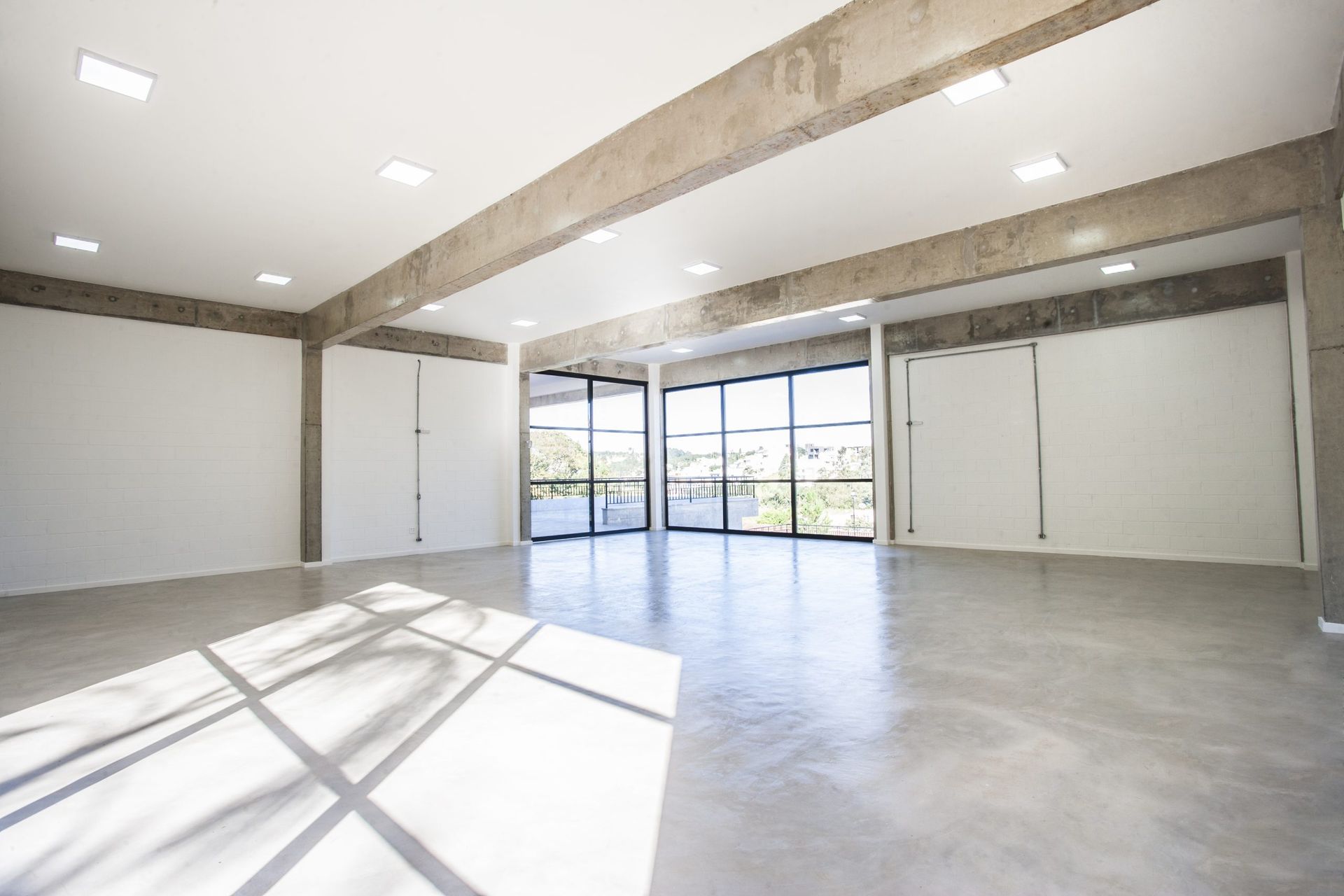 Uma sala vazia com muitas janelas e um piso de concreto