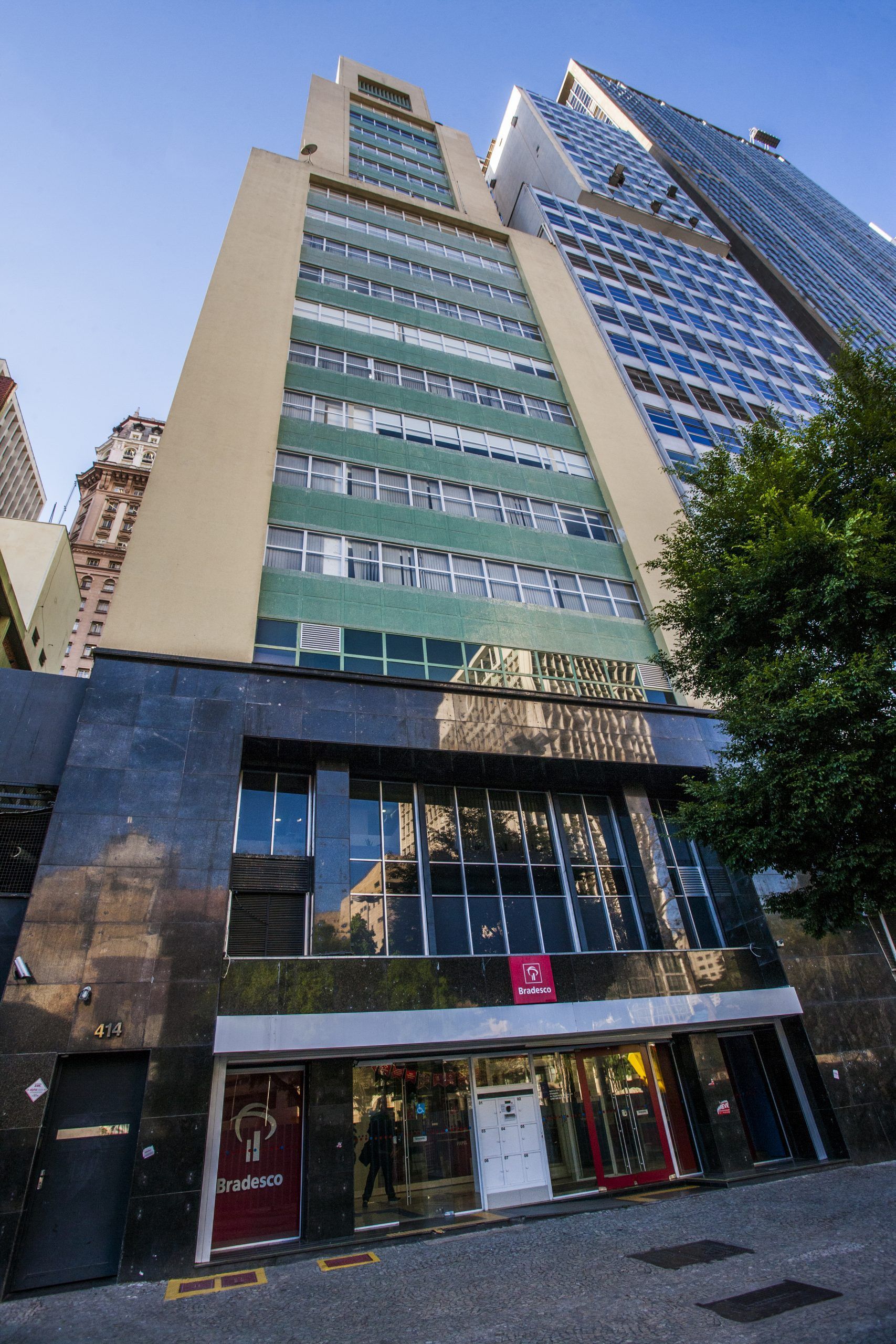 Um edifício alto com muitas janelas está rodeado por outros edifícios