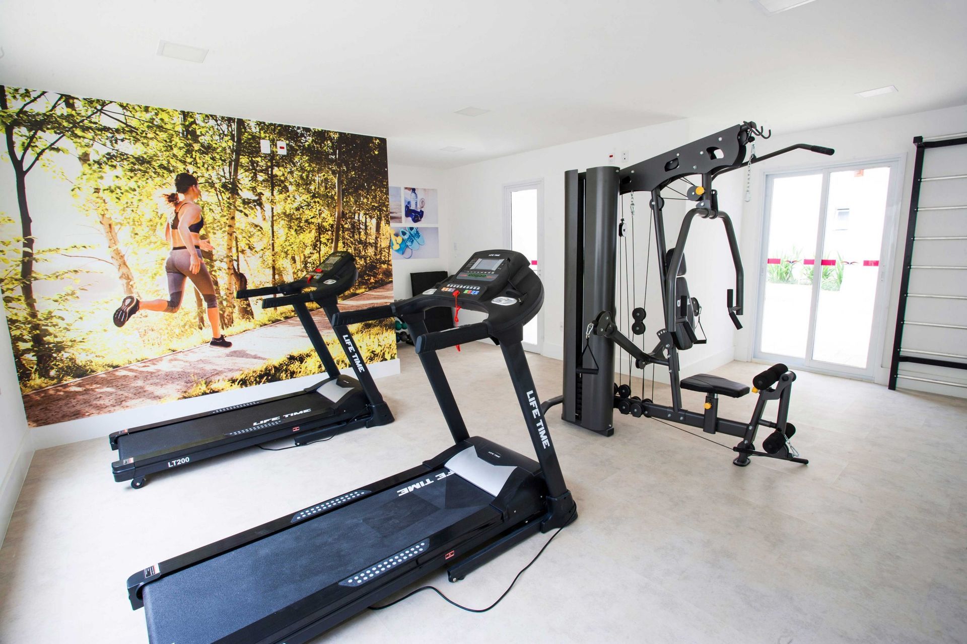 Há duas esteiras em uma academia com uma imagem de uma pessoa correndo na parede.