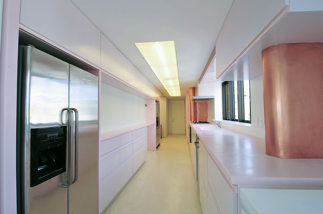 Um longo corredor em uma cozinha com uma geladeira de aço inoxidável