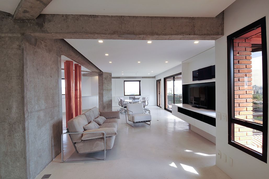 Uma sala de estar com um sofá, cadeiras e uma televisão