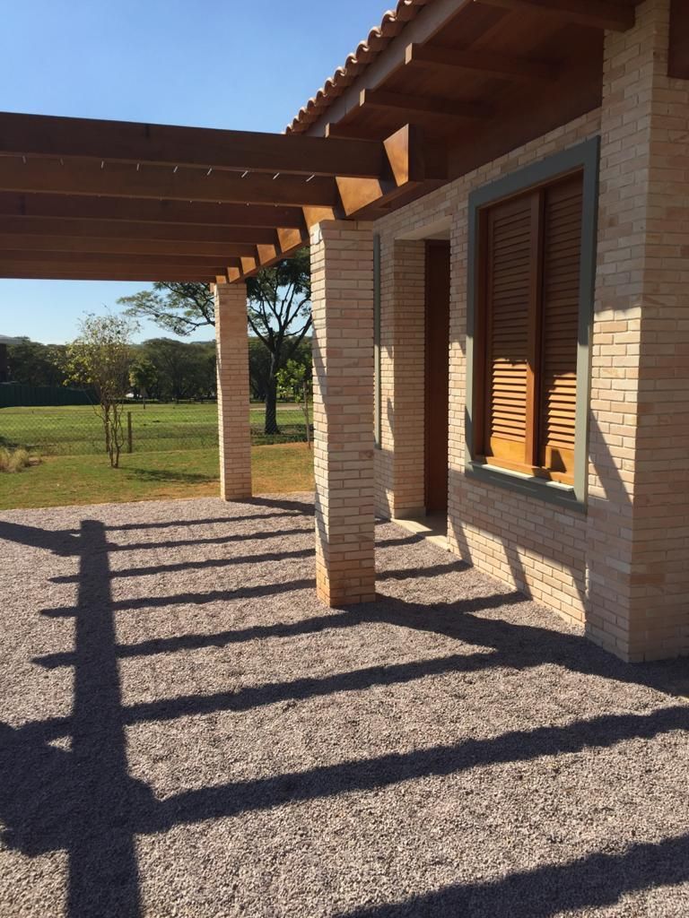 Uma casa de tijolos com uma pérgola de madeira e venezianas nas janelas