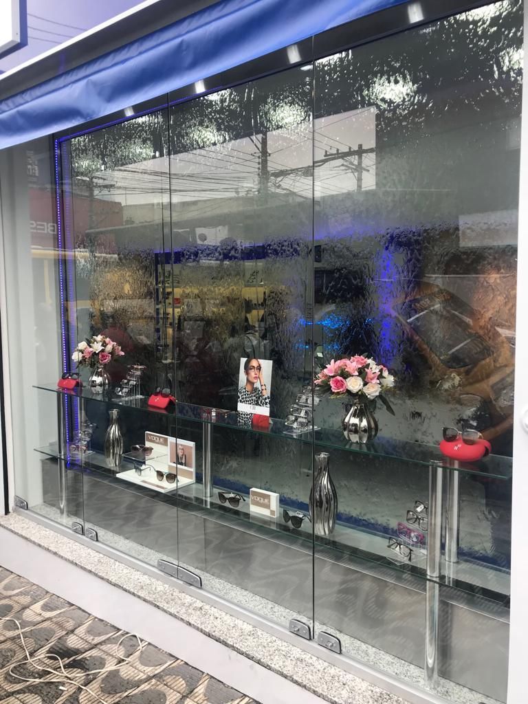 Uma vitrine com flores e óculos de sol em exposição.